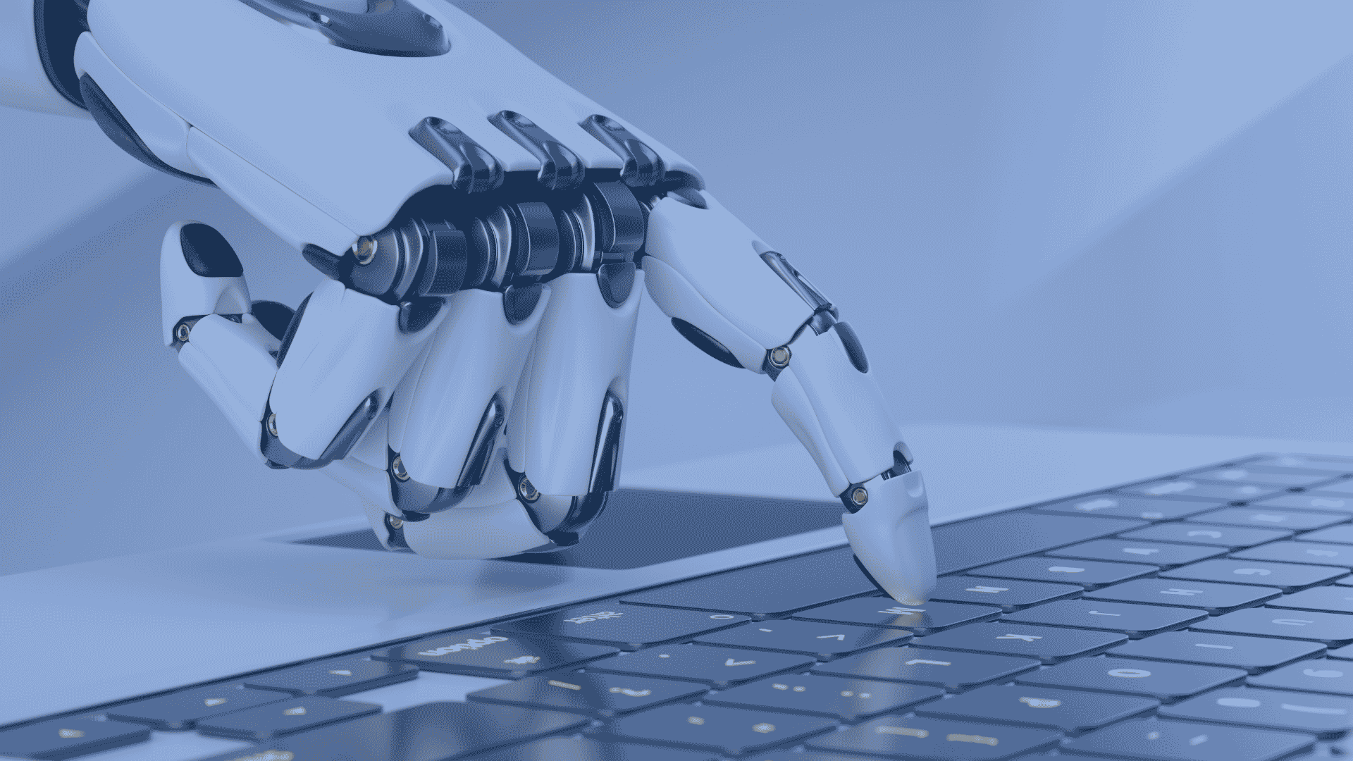 Robotic arm typing on a laptop keyboard, representing AI-driven automation