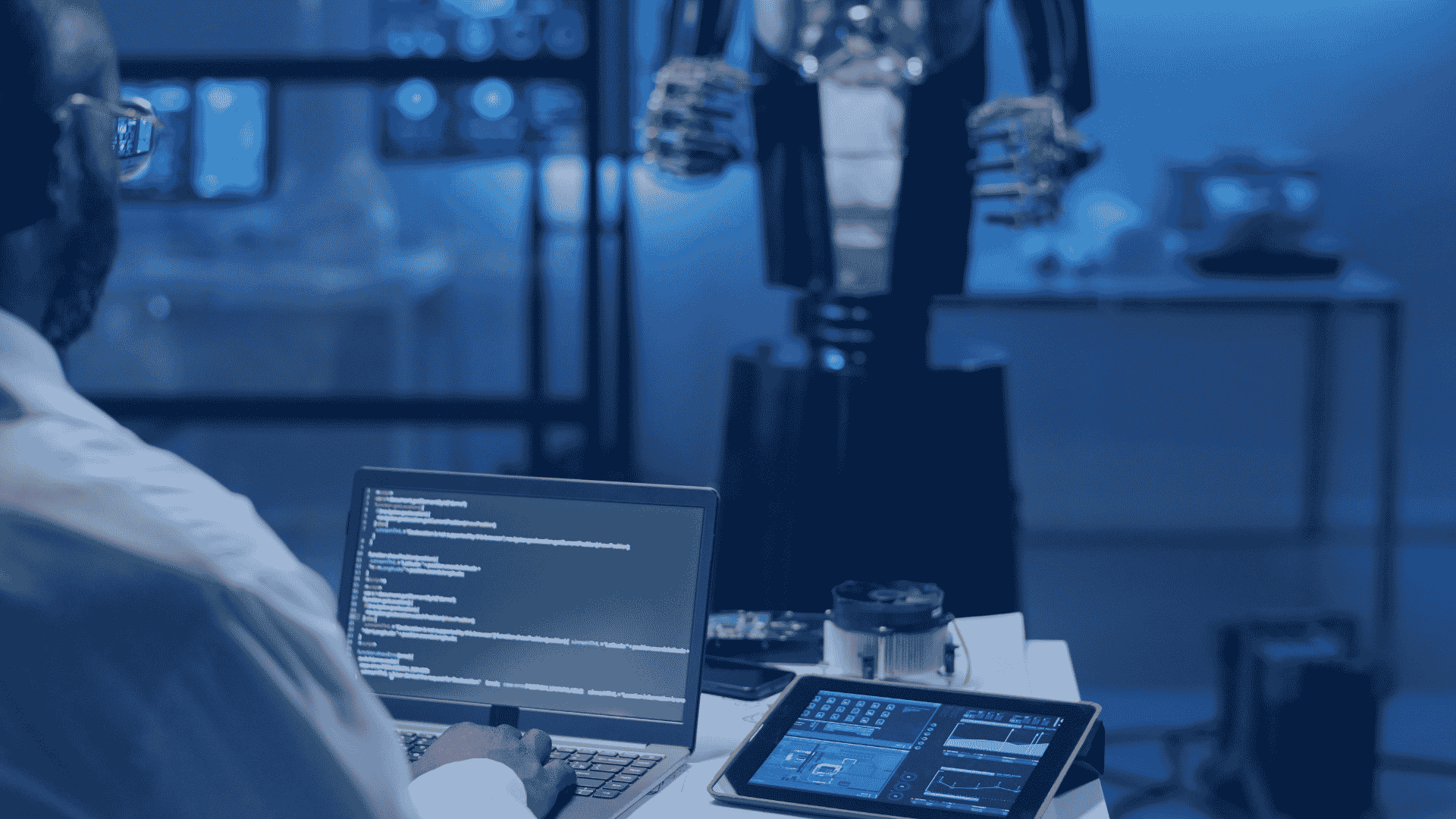 An engineer programming AI automation workflow software on a laptop, with a robotic arm in the background