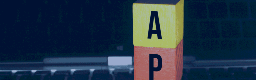 Stacked wooden blocks spelling "API" placed on a laptop keyboard against a dark background.