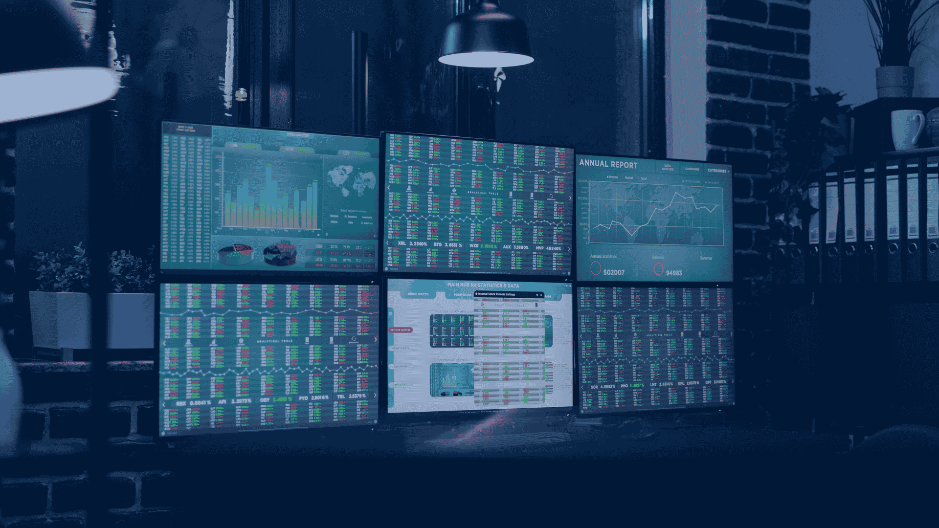 Multi-monitor workstation displaying business analytics dashboards, performance metrics, financial reports, and data visualizations