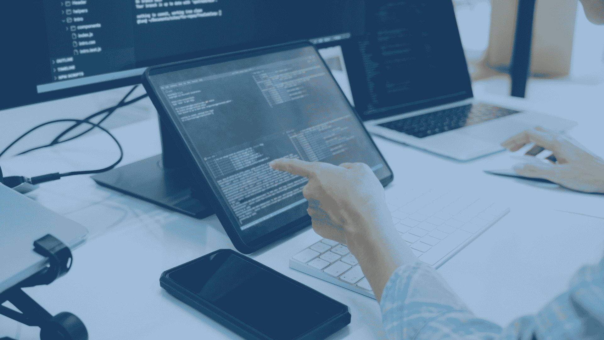 A developer's hand touches a tablet screen displaying code,