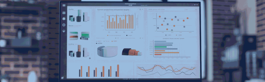 Desktop monitor on a desk showing an analytics dashboard with bar, scatter and line charts in an office with a brick wall